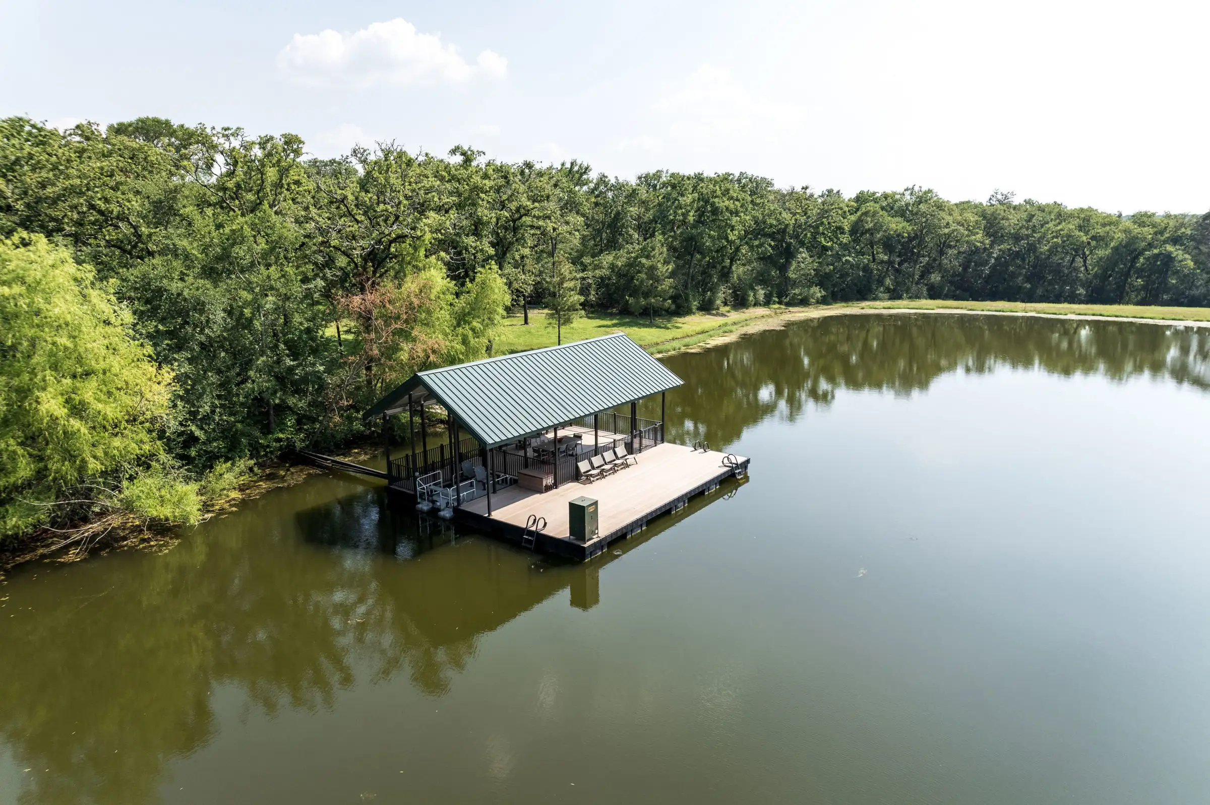 Aerial view of a covered aluminum floating dock on a quiet, tree-lined Texas pond